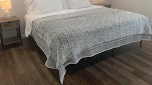 Ein Schlafzimmer mit Bett, Holzboden, Deckenventilator und zwei Nachttischlampen.