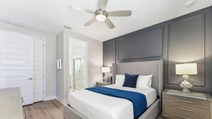 A bedroom with a bed, bedside tables, a ceiling fan, and a door. - Luxury Retreat  7Bd Home - Close to Disney (Kissimmee)