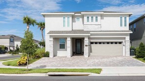 A two-story house with a garage, a front door, and a driveway. - Luxury Retreat  7Bd Home - Close to Disney (Kissimmee)
