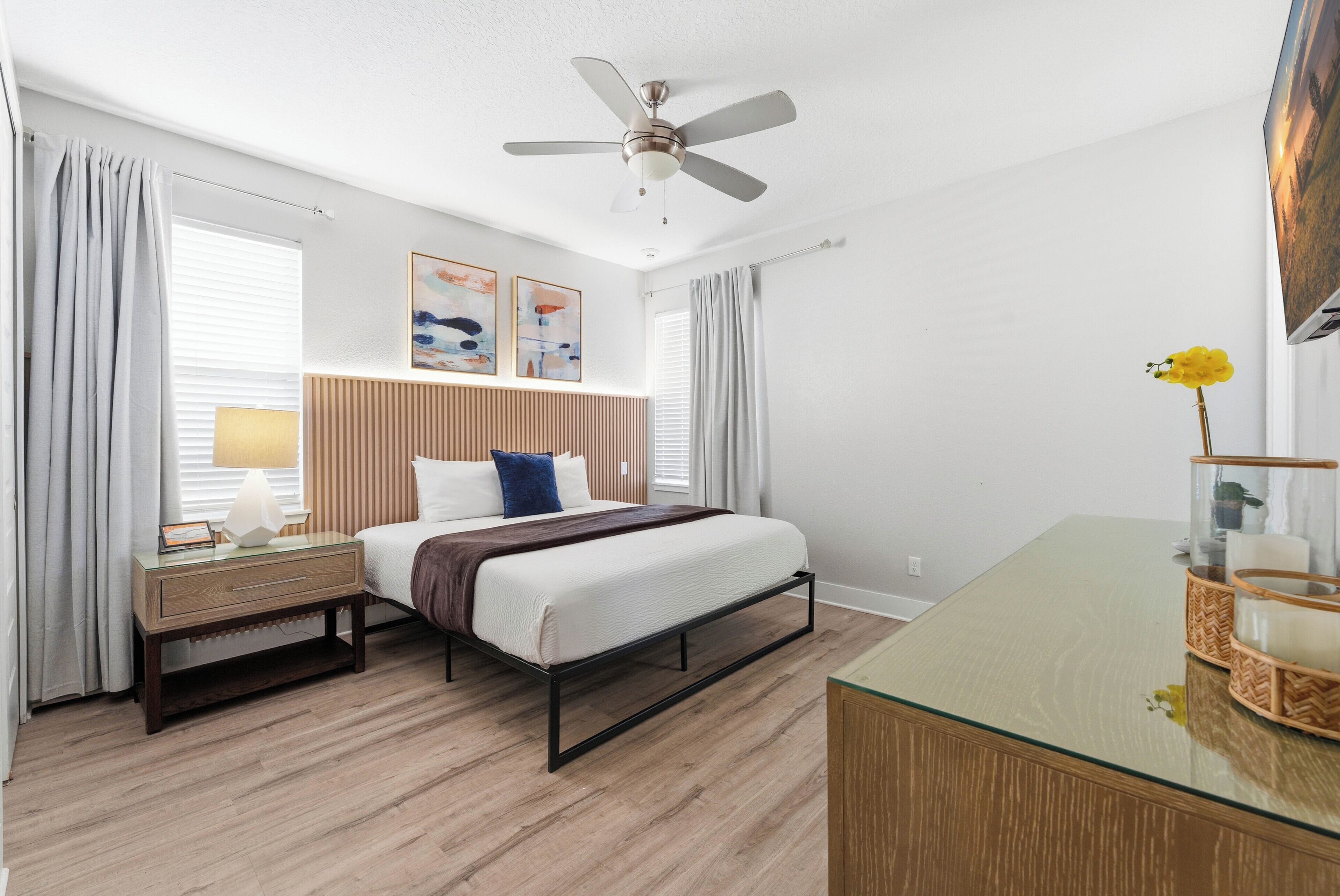 Ein Hotelzimmer mit Bett, Nachttisch, Lampe und Deckenventilator.