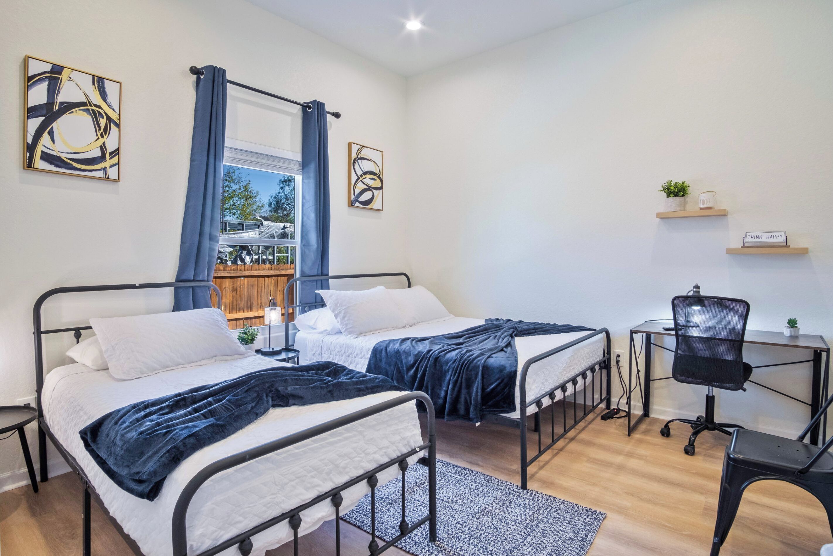 Ein modernes Schlafzimmer mit zwei Betten, einem Schreibtisch und einem Stuhl.