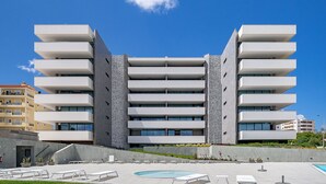 A modern building with multiple balconies and a swimming pool area with sun loungers. - Lagos Deluxe 1 With Pool by Homing (Lagos)