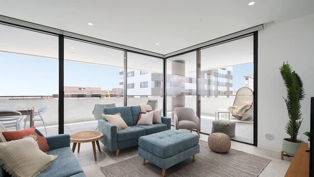 A modern living room with a blue sofa set, a grey armchair, and a round wooden table. - Lagos Deluxe 1 With Pool by Homing (Lagos)