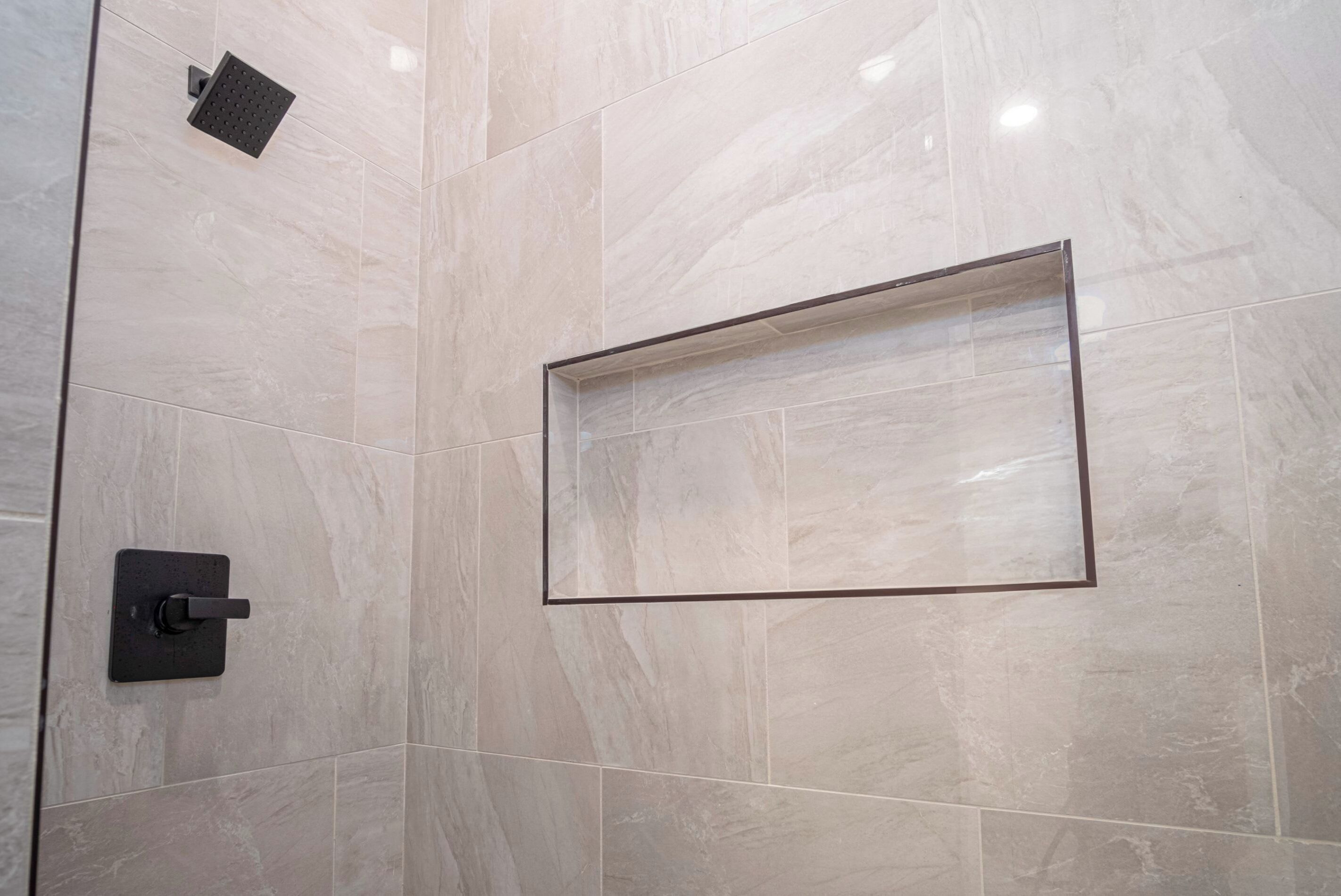Une salle de bain avec un espace douche, un miroir encadré et un panneau de commande fixé au mur.