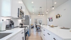 Une cuisine moderne avec des meubles blancs, un îlot central et un coin repas comprenant une table et des chaises.