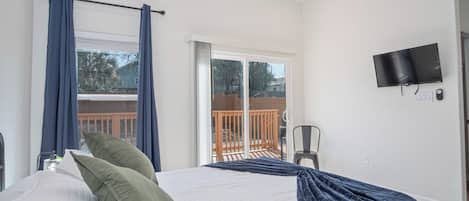 A bedroom with a bed, curtains, a TV, and a balcony with a railing.
