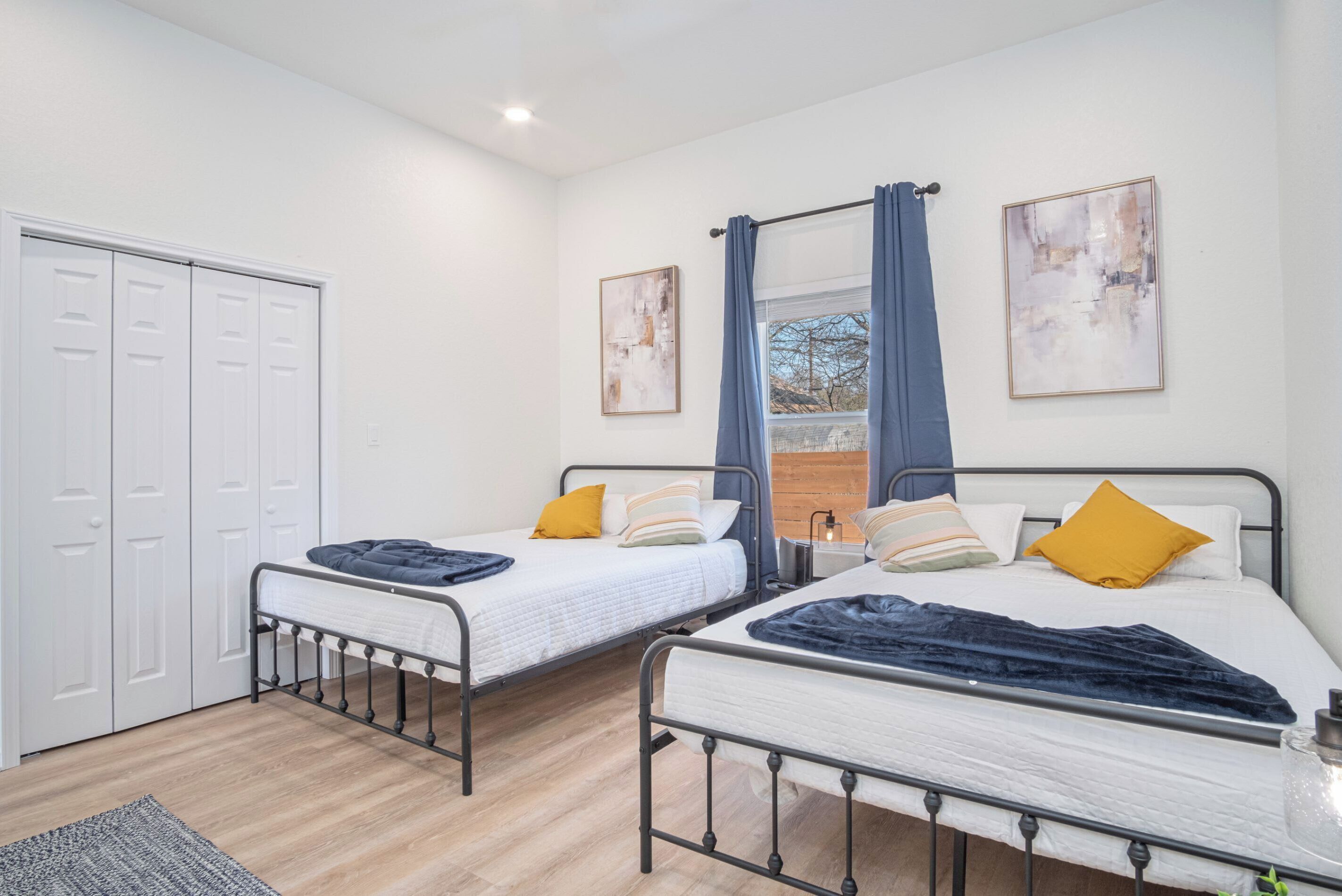 A bedroom with two single beds, a wardrobe, and a window with curtains.