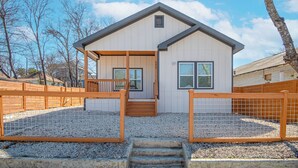 A two-story house with a front porch, wooden fence, and gravel driveway. - Feel, Chill and Enjoy 4br/3ba Near Fun Riverwalk! (San Antonio)