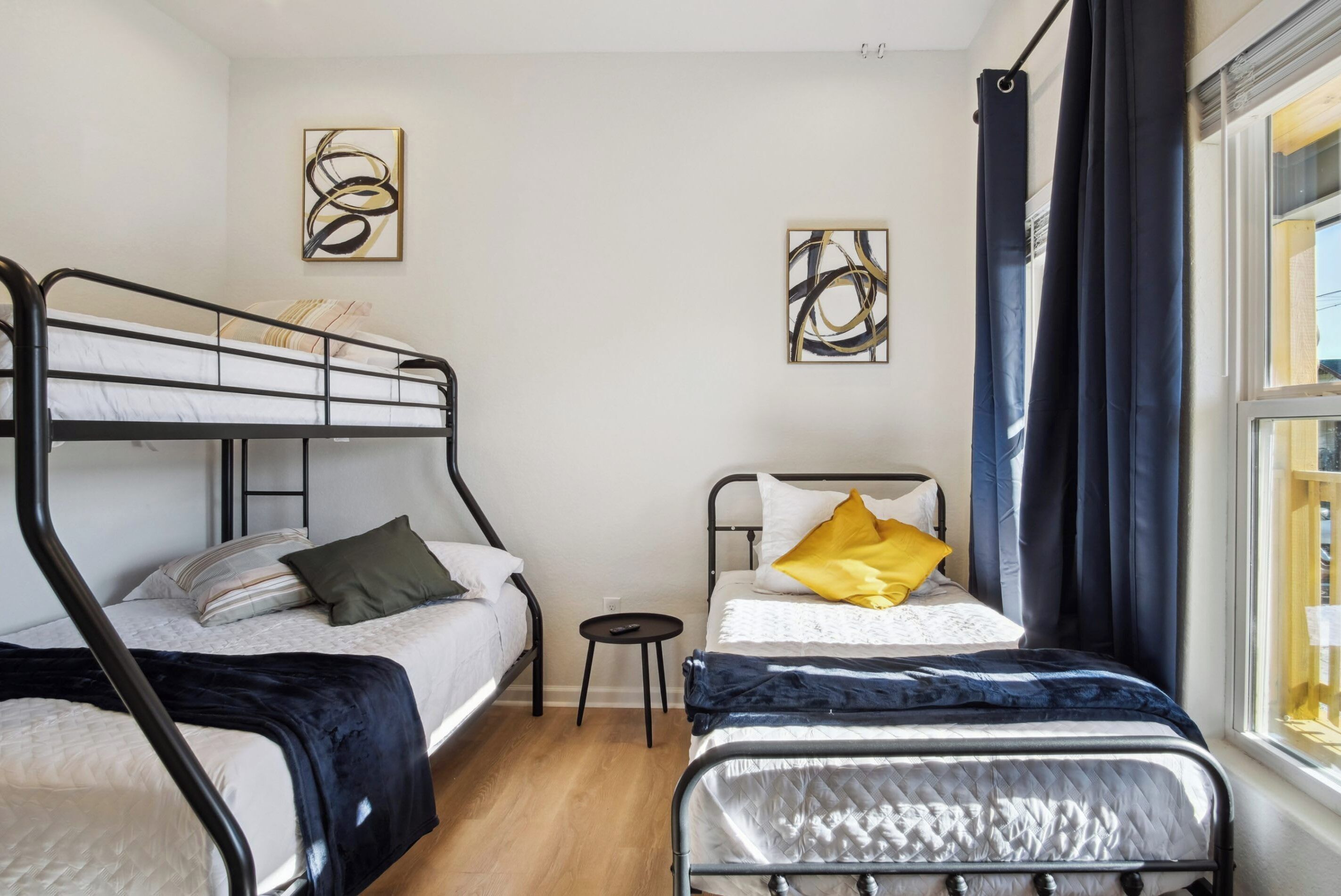 A room with bunk beds, a small table, and artwork on the walls.