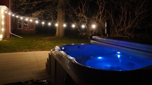 A hot tub with a blue light, surrounded by a deck and string lights. - Historic Whiffletree place, 4br, riverview, no neighbors (Sparland)