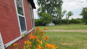 A red building with a window and a garden with orange flowers. - Historic Whiffletree place, 4br, riverview, no neighbors (Sparland)