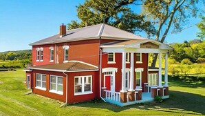 A two-story house with a red exterior and white trim, featuring a covered porch with a brick base and white columns. - Historic Whiffletree place, 4br, riverview, no neighbors (Sparland)
