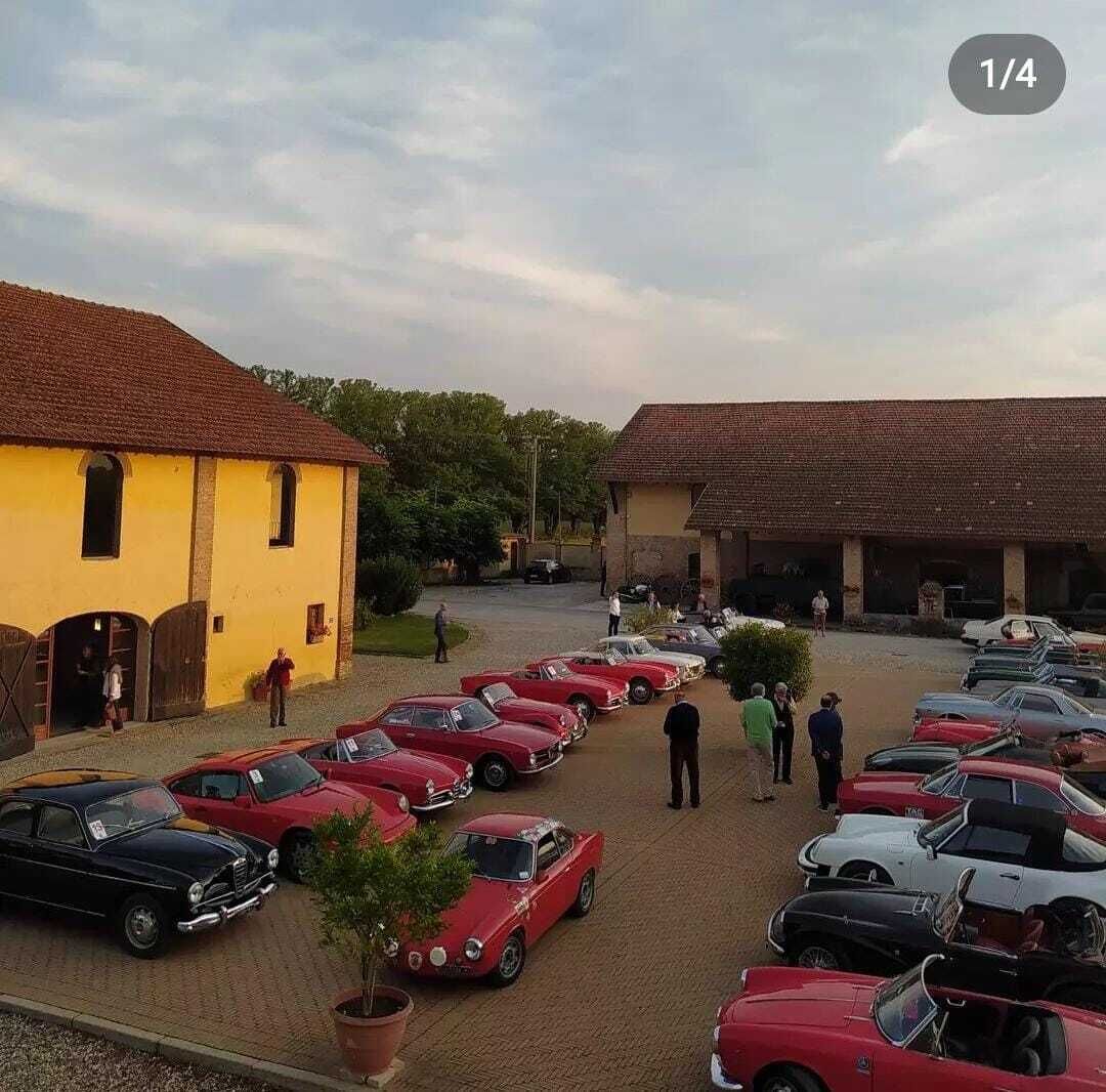 A parking lot with vintage cars, a yellow building, and a red-roofed structure.