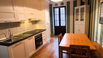 A kitchen with white cabinets, a black countertop, and a wooden dining table with chairs.