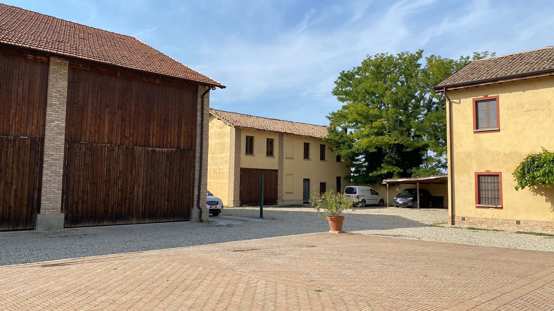 A courtyard with buildings, a parked van, and a potted plant.