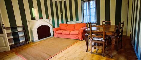 Una habitación con chimenea, un sofá, una mesa de comedor con sillas y una pared a rayas.
