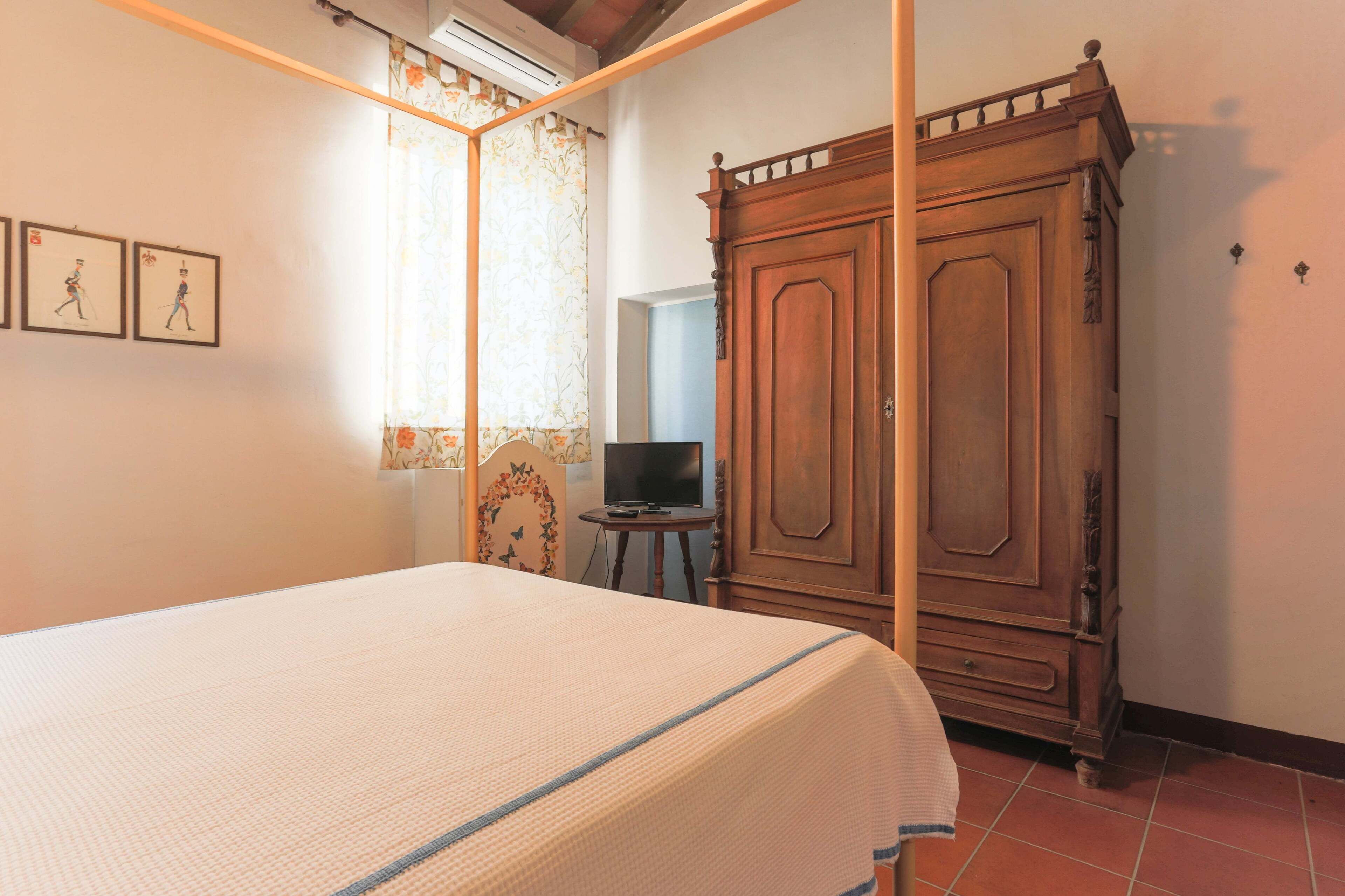 A bedroom with a bed, wardrobe, and a television on a small table.