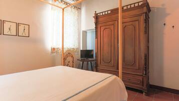 A bedroom with a bed, wardrobe, and a television on a small table.