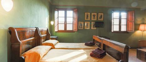 Una habitación con dos camas de madera, un escritorio de madera, una silla y una lámpara.