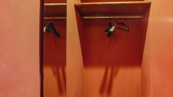 Une petite pièce fermée, avec un banc en bois, un miroir et une étagère où sont accrochés divers objets.