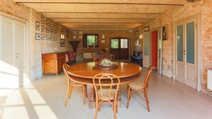 A dining area with a brick wall, wooden dining table, and chairs. - AGRITURISMO LE CORTI DELLA GUALDANA (Voghera)
