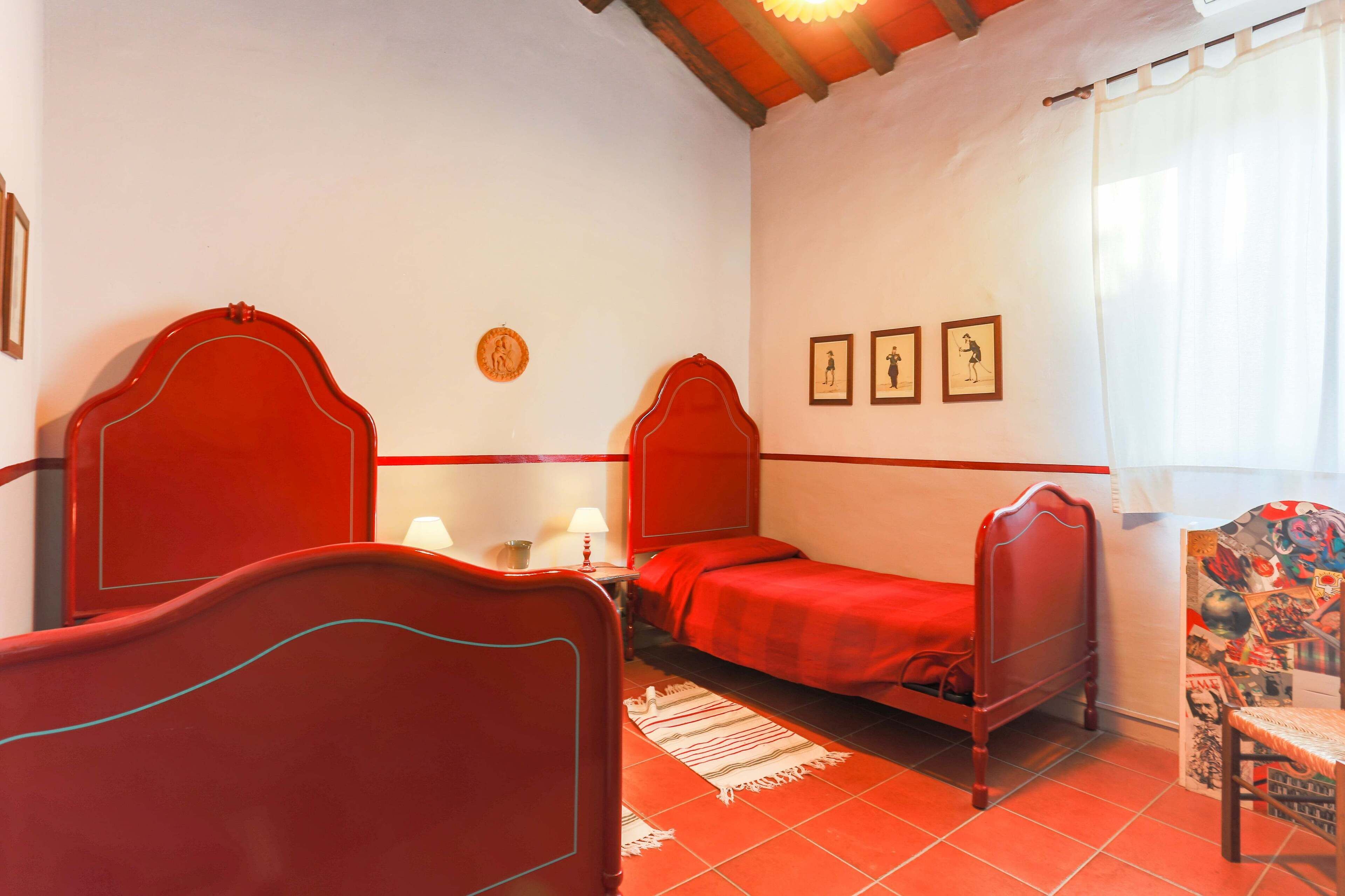 Una habitación con dos camas de madera, una mesita con lámpara y una silla de diseño llamativo.