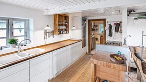 A modern kitchen with white cabinetry, wooden countertops, and a built-in stove. - 4 Star Holiday Home in Laeso (Læsø)
