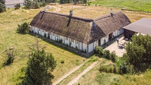 A thatched-roof farmhouse with a long, narrow structure, surrounded by a rural landscape. - 4 Star Holiday Home in Laeso (Læsø)