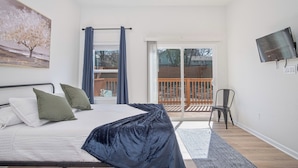 A bedroom with a bed, a TV, a painting, and a balcony with a view. - Feel, Chill and Enjoy 4BR/3BA Near Fun Riverwalk! (San Antonio)