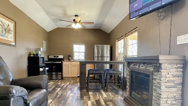 A spacious living area with a fireplace, a kitchen with modern appliances, and a comfortable seating area. - Country Cabin in Private Setting (Altha)