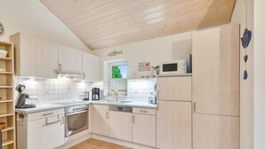 A modern kitchen with light wood cabinets, a stainless steel oven, and a microwave. - 4 Star Holiday Home in Ottendorf (Otterndorf)