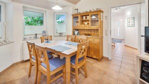 A kitchen with wooden cabinets, a dining table with chairs, and a television. - 4 Star Holiday Home in Ottendorf (Otterndorf)