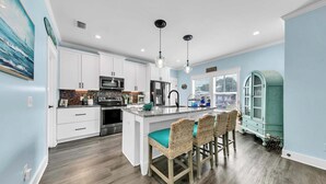 A modern kitchen with white cabinets, stainless steel appliances, and a central island with bar stools.