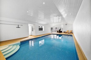An indoor swimming pool with clear water, a wooden deck, and lounge chairs. - 3 Bed in Plympton (oc-m30351) (Sparkwell)