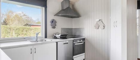 A modern kitchen with a large window, a built-in oven, and a stove.