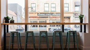 A bar area with four stools and a window overlooking Downie Street Burgers. - Plums Unit 3: Downtown King (Stratford)