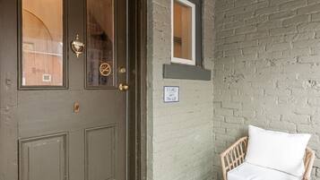 A door with a brass handle and a window, a wicker chair with a cushion, and a sign indicating "Unit 3 The Loft".