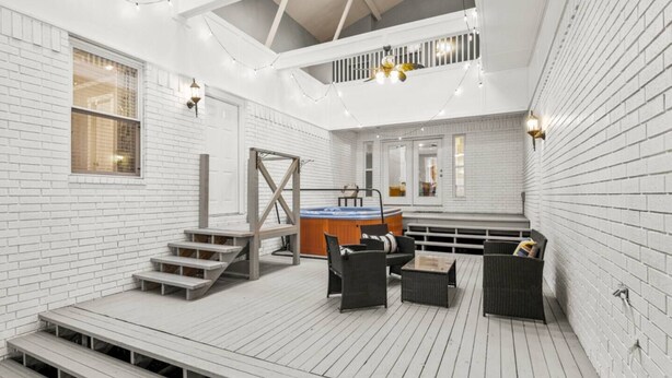 Une vaste terrasse dotée d’un jacuzzi, d’un espace salon et d’un escalier menant à un niveau supérieur.