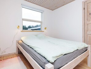 A bedroom with a single bed, a window, and a wooden door.