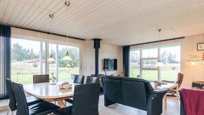 Una sala moderna con comedor, ventanas amplias y chimenea.