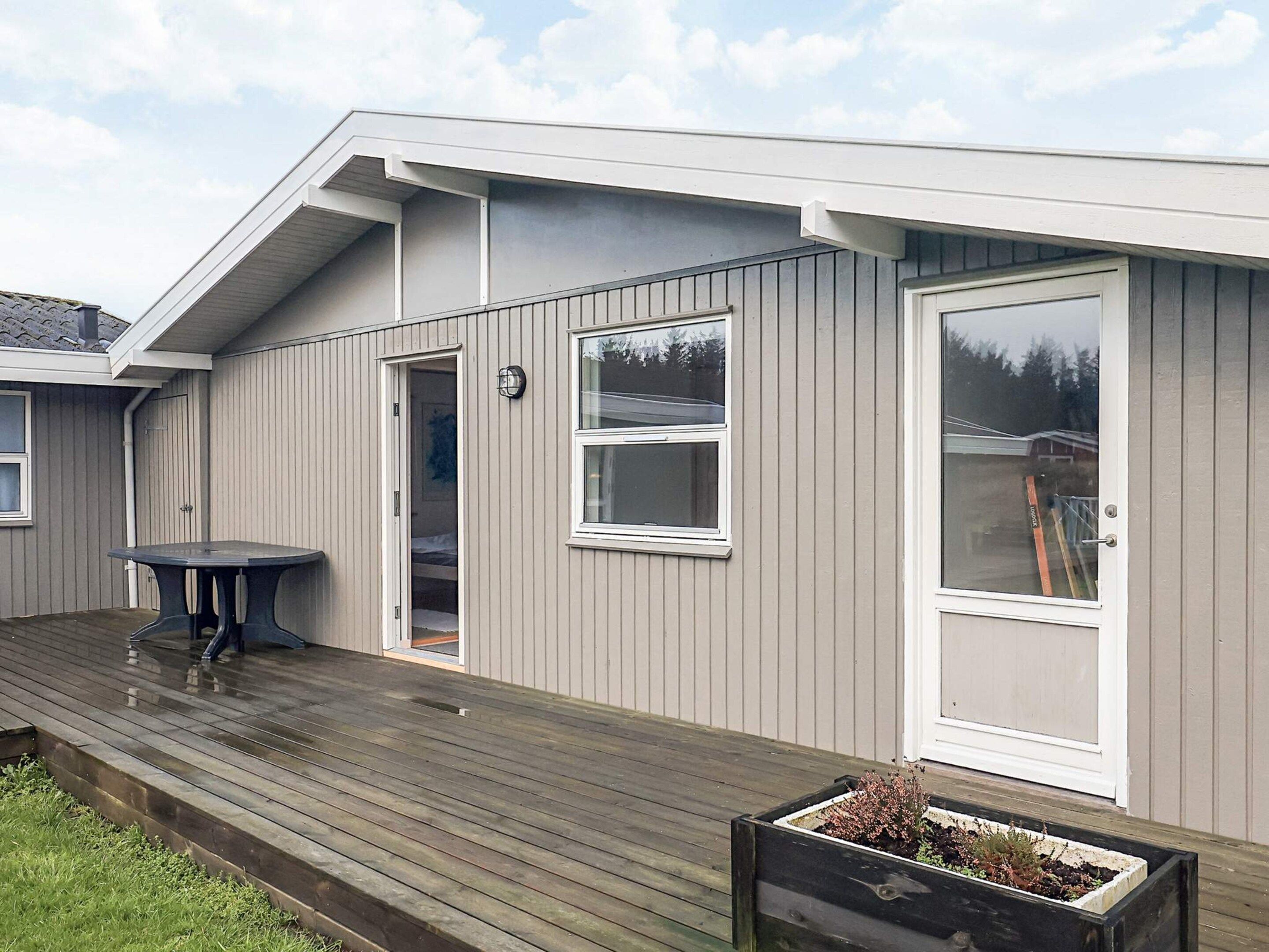 A residential building with a wooden deck, a door, and a window.