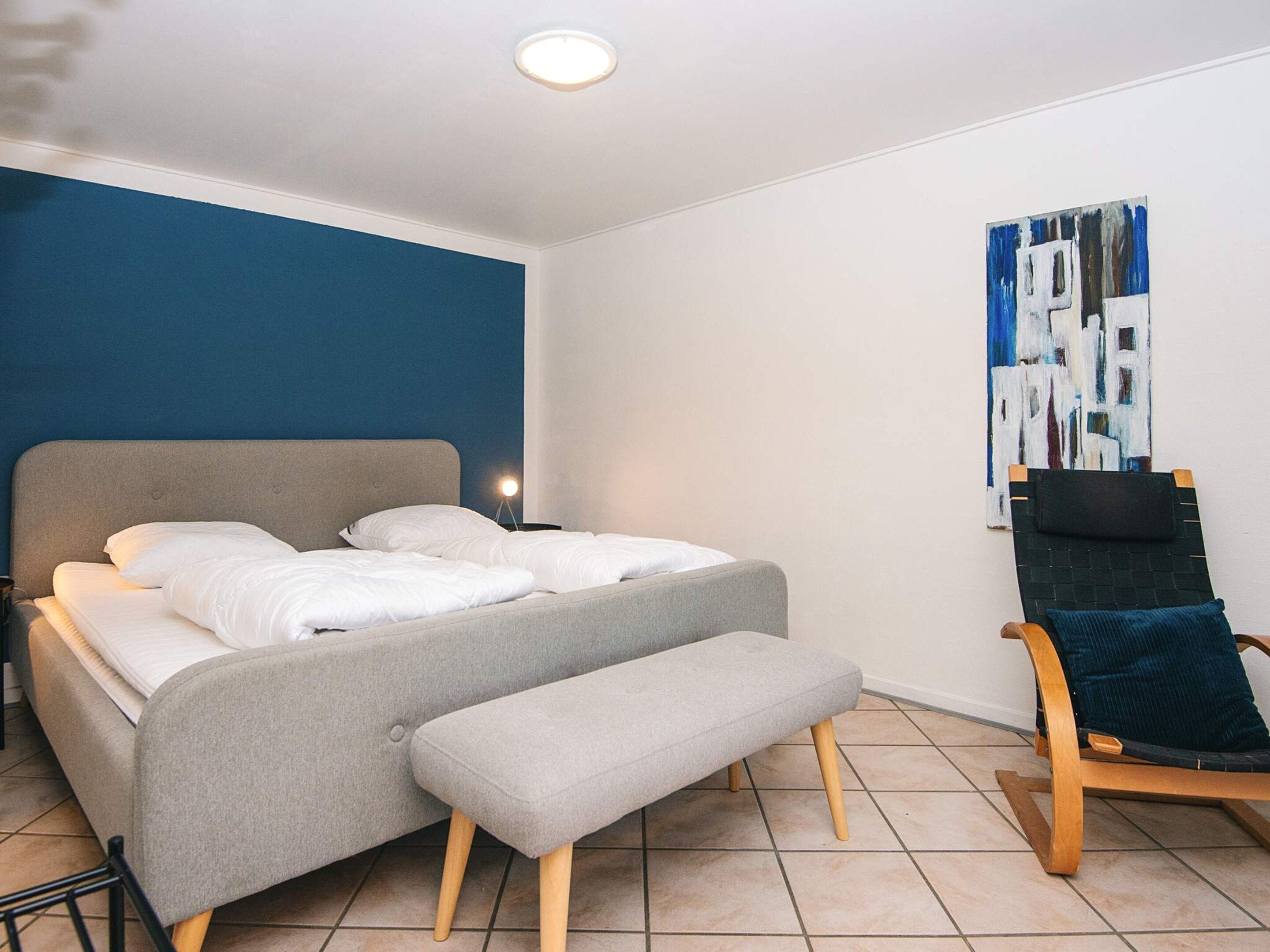 Un dormitorio moderno con cama, banca y una silla.
