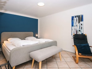 A modern bedroom with a bed, bench, and a chair.