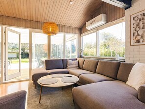 Ein modernes Wohnzimmer mit einem Ecksofa, einem runden Couchtisch und einer Hängeleuchte.
