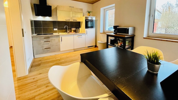 Una cucina moderna con mobili bianchi, un piano di lavoro nero e un soffitto in legno.