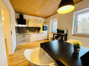 Moderni keittiö, jossa on valkoiset kaapit, musta työtaso ja puinen katto.