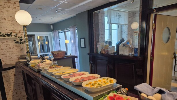 A buffet setup with various food items and a mirror reflecting the room. - Hotel New Bed (Oskarshamn)