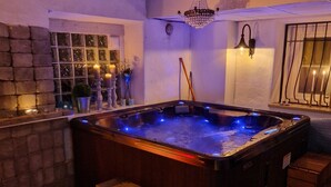 A hot tub with blue LED lights, a wooden bench, and a stone wall. - Hotel New Bed (Oskarshamn)
