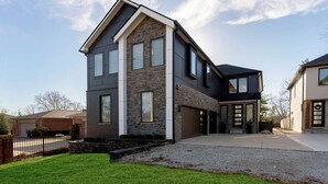 A modern two-story house with a stone facade, a garage, and a well-maintained lawn.