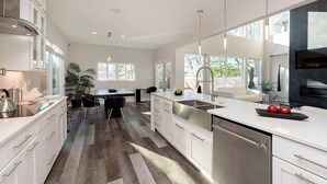 A modern kitchen with white cabinetry, a central island, and a dining area with a table and chairs.
